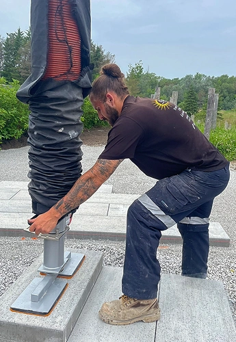 sunready landscaping man is installing a metal pole on a concrete base