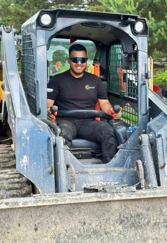 sunready landscaping man wearing sunglasses is seated in a skid steer